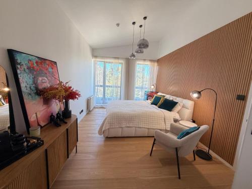 a bedroom with a bed and a chair in it at White & Wood Suite C302, at Euphoria SPA Borovets in Borovets