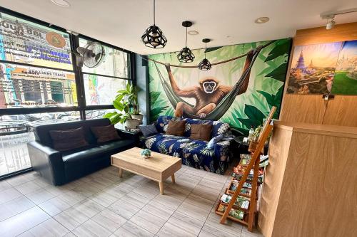 a living room with a monkey painting on the wall at Lazy Gibbon 1 Chiang Mai - Tha Phae Gate in Chiang Mai