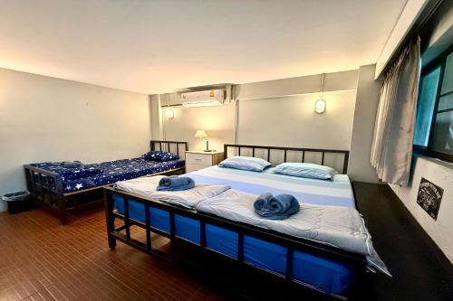 two beds in a room with blue towels on them at Lazy Gibbon 1 Chiang Mai - Tha Phae Gate in Chiang Mai