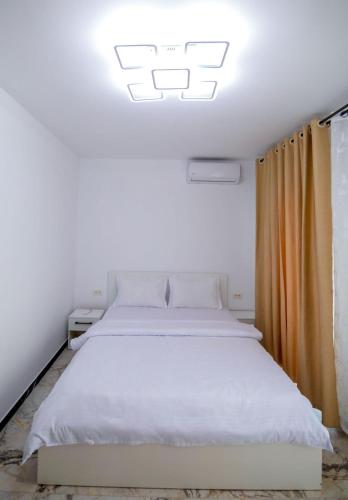 a bedroom with a large white bed with an orange curtain at Nibiru Sea View in Costinesti
