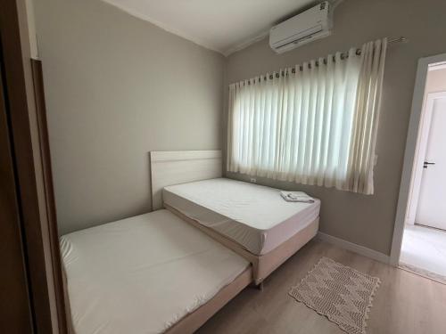 two beds in a small room with a window at casa da piscina e churrasco in Maringá