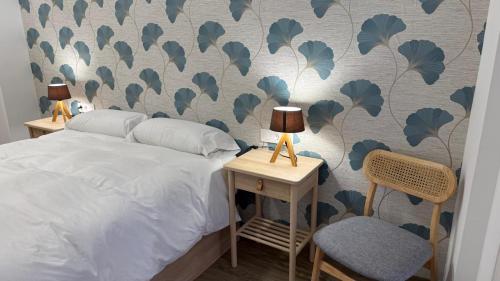 a bedroom with a bed and a wall with a leafy wallpaper at Rincón Mudejar in Teruel