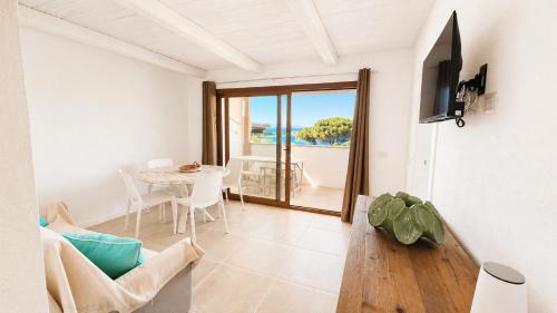 a living room with a table and a view of the ocean at Rena Bianca Residence 225 in Baja Sardinia