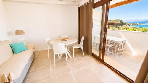 a living room with a table and chairs and a window at Rena Bianca Residence 225 in Baja Sardinia