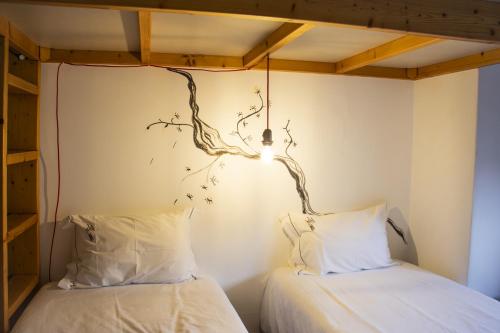 two beds in a room with a branch on the wall at Collector's Home in Braga