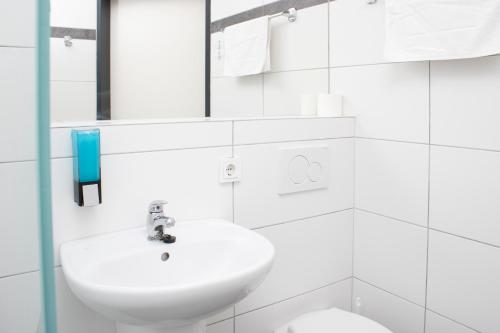 a white bathroom with a sink and a toilet at OEKOTEL Hohenems in Hohenems