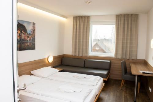 a hotel room with two beds and a desk at OEKOTEL Hohenems in Hohenems