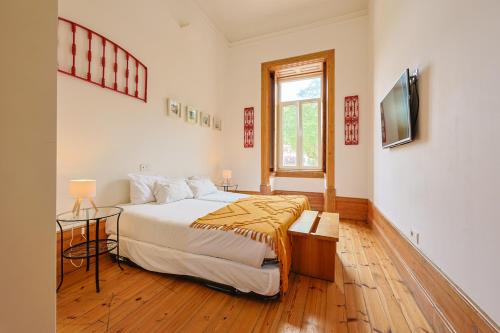 a bedroom with a large bed and a television at Casa da Praça by PURUS in Coimbra