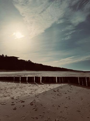 a beach with footprints in the sand and the ocean at Paula Wellness & SPA in Pobierowo