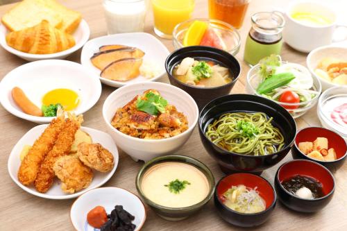 a table with plates of food and bowls of food at Dormy Inn Express Kakegawa in Kakegawa