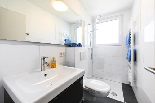 a white bathroom with a sink and a toilet at Appartementanlage Wieben in Böhl