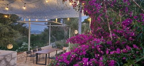 a patio with purple flowers and a table and chairs at Villa Maya Lefkada in Évyiros