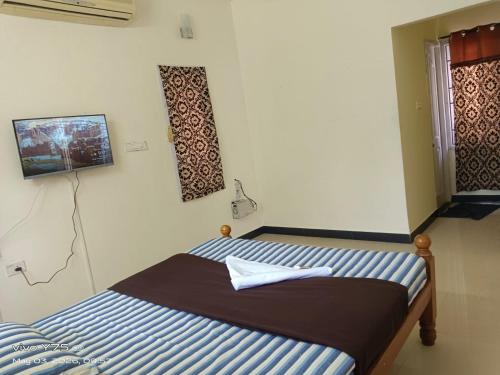 a bedroom with a bed and a tv on the wall at Green Haven Villas in Chennai