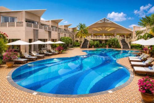 a swimming pool at a resort with chairs and umbrellas at Sterling Puri in Puri