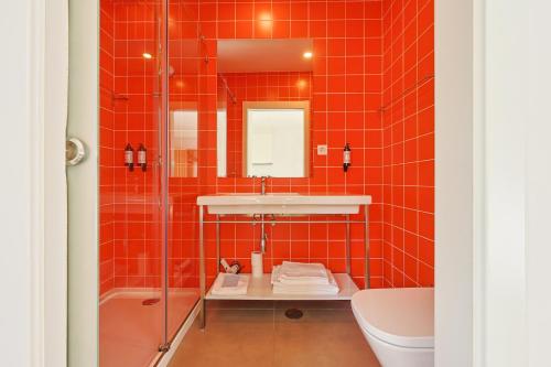a red tiled bathroom with a sink and a tub at Casa da Praça by PURUS in Coimbra