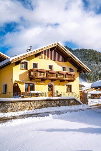 a large yellow house with snow on the ground at Ferienwohnung Sonnenbichl in Schattwald