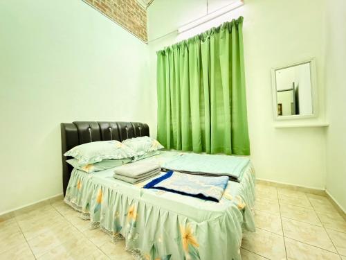 a bedroom with a bed with a green curtain at Lanang Islamic Homestay in Bedung