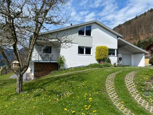 a white house on top of a grassy hill at Apartment Marialis in Bizau