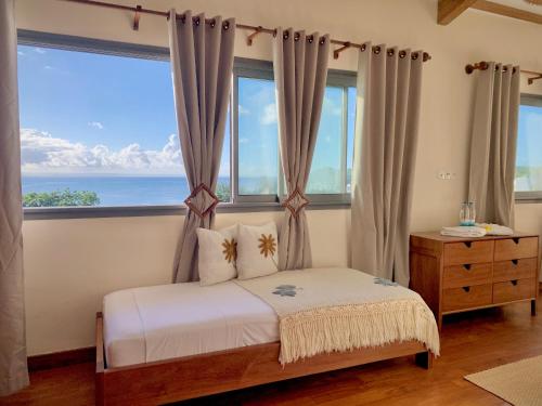 a bedroom with a bed and a large window at La Colombine Appart'Hôtel in Sainte Marie