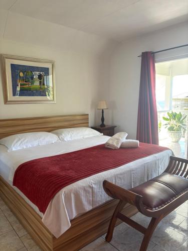 a bedroom with a large bed with a chair and a window at Touchdown Villa in Pointe Larue
