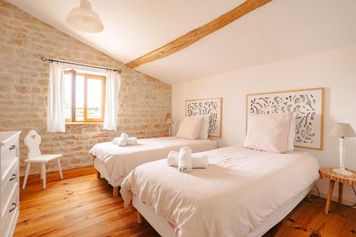 two beds in a room with white walls and wooden floors at Opaline à la Rochelle in Vergné