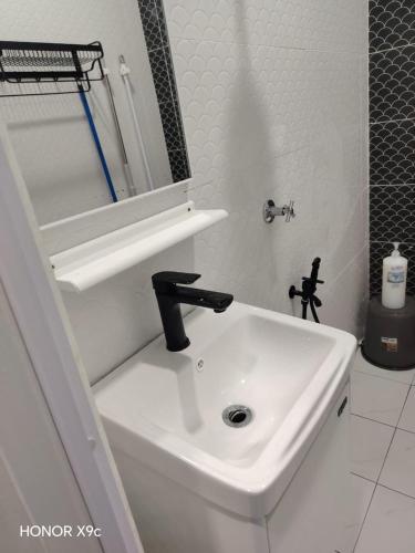 a white bathroom with a sink and a mirror at ZIRA STAY PENARIK - Ziyad Room in Kampong Ru Sepuloh