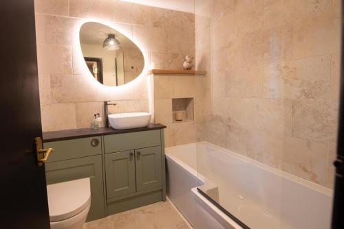 a bathroom with a tub and a sink and a bath tubermottermott at Green Beck Cottage, within walking distance of the lake, shops, pubs & restaurants of Coniston in Coniston