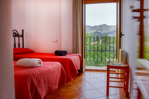 a bedroom with two beds and a large window at La Casa del Carrebaix in Orba