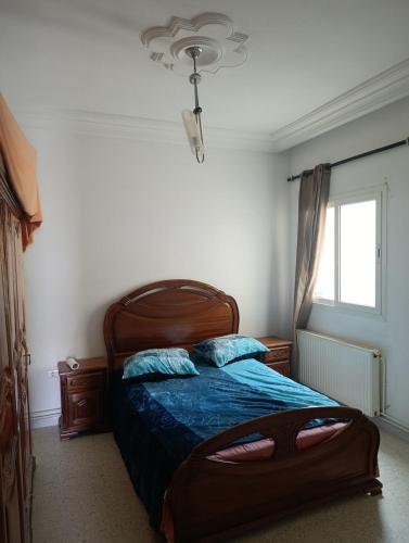 a bedroom with a bed with blue sheets and a window at Cozy house in Nabeul
