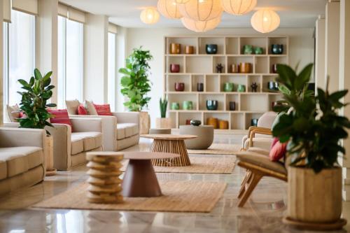 a living room with couches and tables and plants at Alua Leo in Can Pastilla