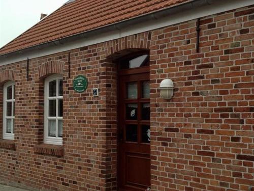 a brick building with a brown door and a window at Klaassen- Ferienhaus Up Warf in Emden