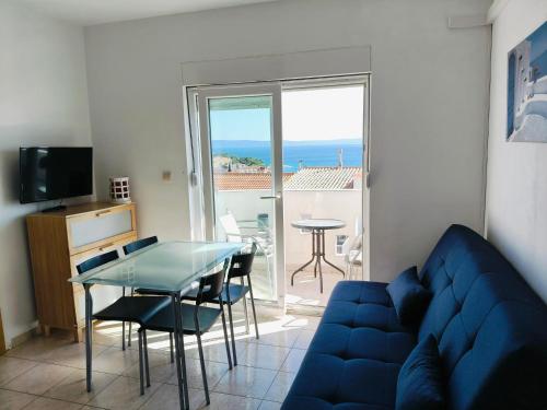 a living room with a blue couch and a glass table at Apartments Malou in Baška Voda