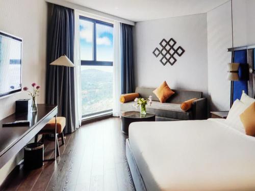a hotel room with a bed and a couch at Pristine Coast Residences in Phan Thiet