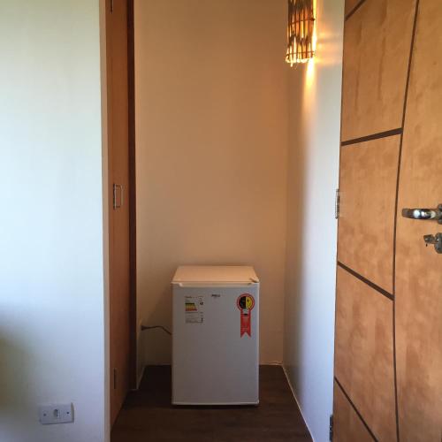 a small refrigerator in a hallway with a door at Suites na Casa da Praia in Ilhabela