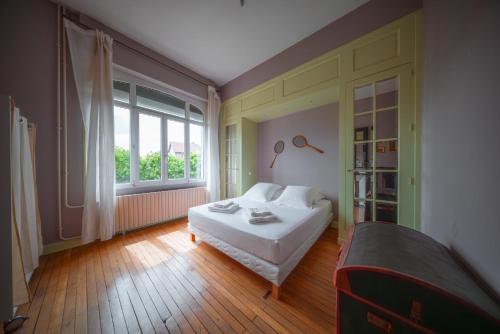 a bedroom with a white bed and a window at Le Grand Rivage in Verdun-sur-Meuse