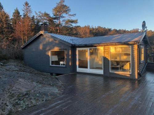 a small house with a deck in front of it at Havblikk, cozy cabin by the sea with beautiful views in Mandal