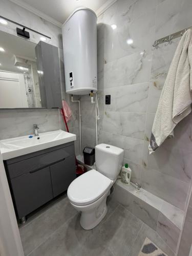 a bathroom with a white toilet and a sink at Apartament Rîșcani in Chişinău