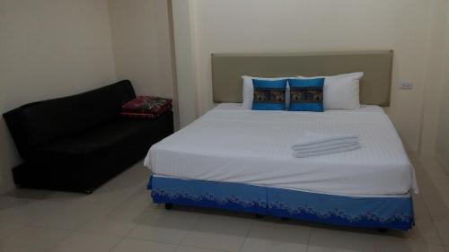 a bedroom with a large bed and a black chair at Wattana Bungalow in Nai Yang Beach