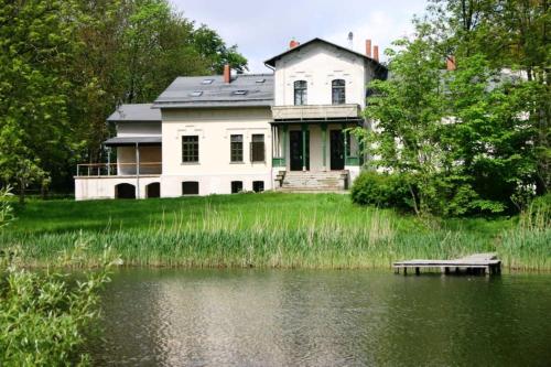 a white house sitting on the side of a lake at Gutshaus Bartelshagen in Bartelshagen
