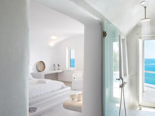 a white bedroom with a view of the ocean at Mykonos Blu, a Resort to Live in Psarou