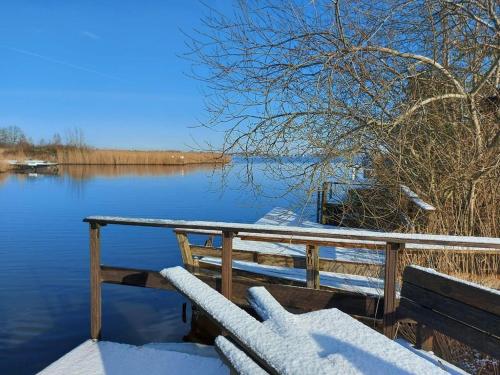 a snowy dock with a boat on the water at Ferienhaus Hieve in Marienwehr