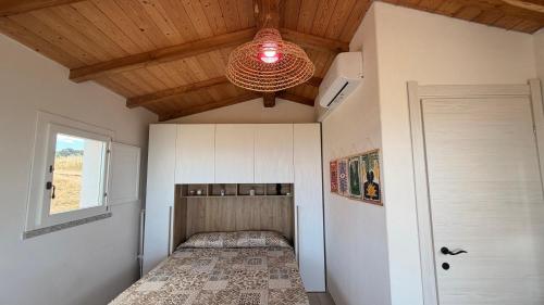 a room with a bed and a ceiling with a chandelier at Isola Rossa Appartamenti vista mare in collina in Isola Rossa