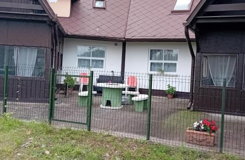a fence in front of a house with a table and chairs at Plázs Vendégházak 1 ,2 in Tiszafüred