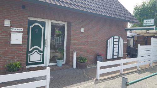 a brick building with a door and a white fence at Bastan - Haus Katharina in Emden