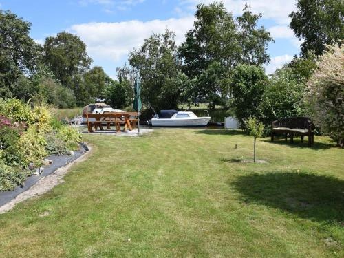 a garden with a table and a boat in the background at Ferienhaus An der Riede in Bedekaspel