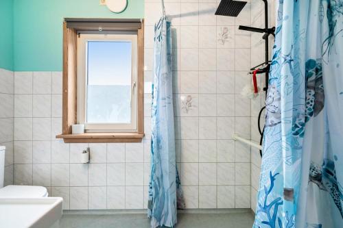 a bathroom with a blue shower curtain and a window at Ferienwohnung Saustrup in Saustrup