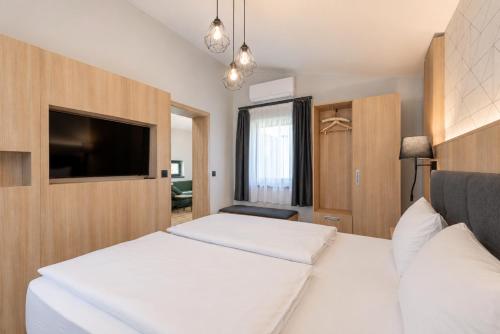 a bedroom with two beds and a flat screen tv at AquaMed Hotel Harkány in Harkány