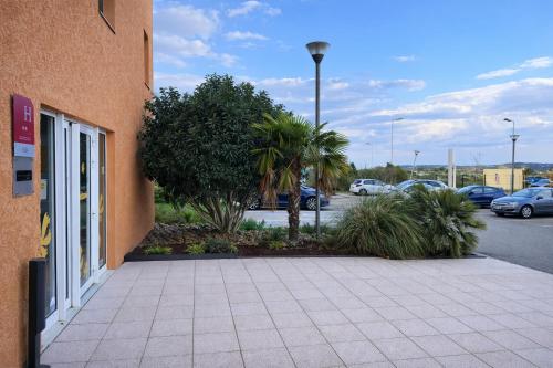 a sidewalk next to a building with a parking lot at HubOne3 Istres in Istres