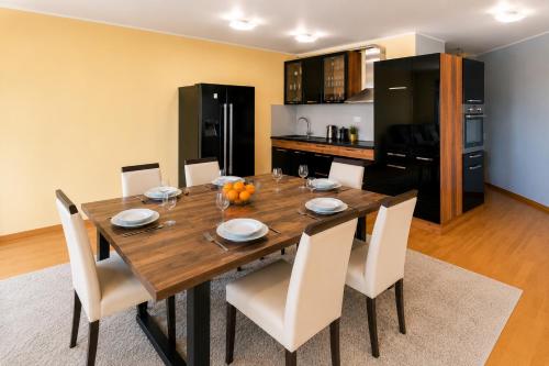 a dining room table with white chairs and a kitchen at Krimovica Sunset Spacious Apartment with Sea View and Pool in Krimovice