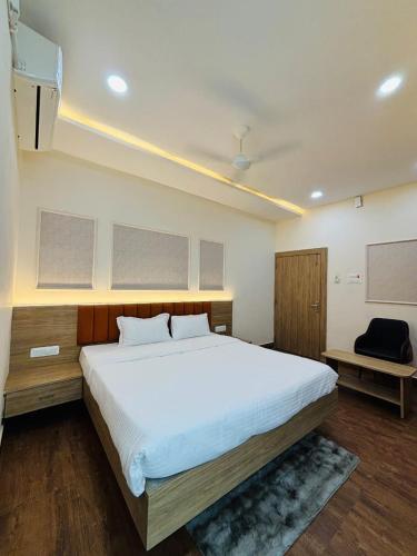 a bedroom with a large white bed and a chair at Hota Residency in Sonepur